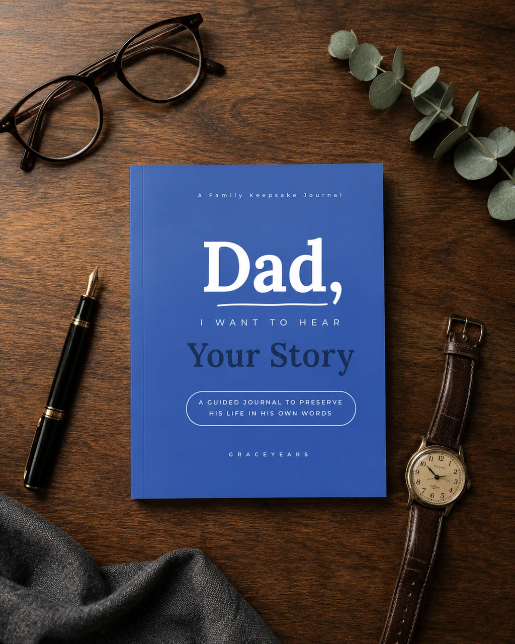 Flat lay of the Dad guided journal with reading glasses, fountain pen and a leather-strap watch