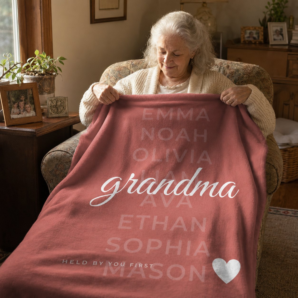 Grandmother in an armchair holding a terracotta fleece blanket printed with her grandchildren's names