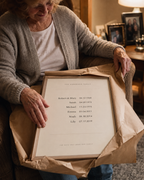 A woman in her seventies unwrapping the framed family dates print as a gift