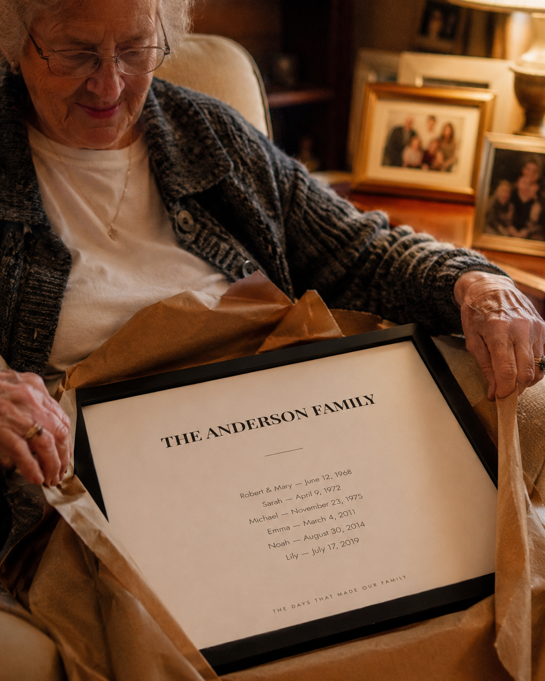 A woman in her seventies unwrapping the framed family dates print as a gift